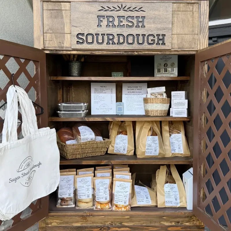 The wood Bread Shed cabinet at Huntsville Mercantile stocked with packaged bread and baked goods