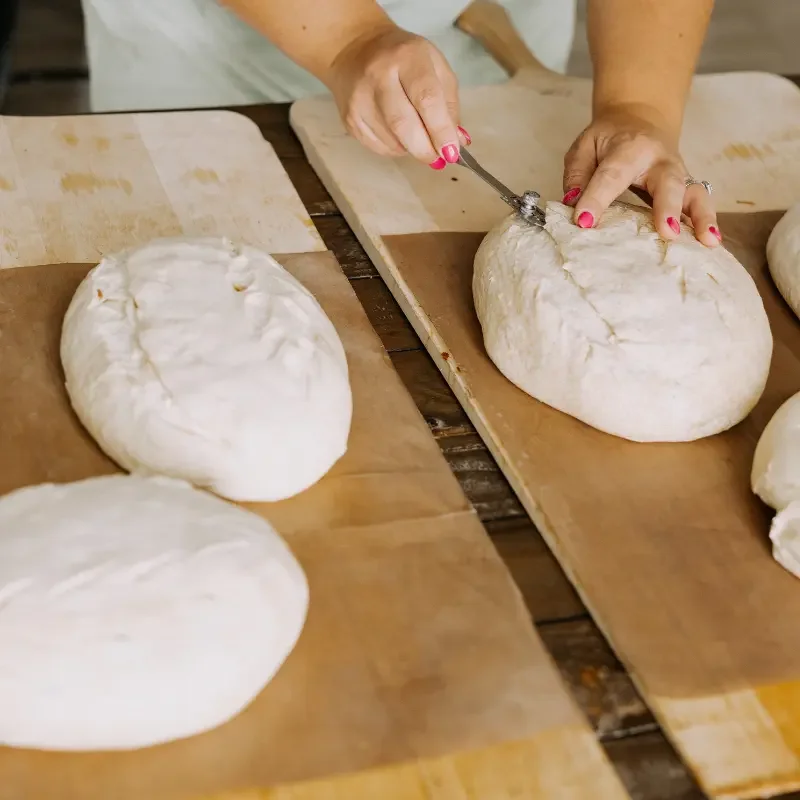 Hands scoring sourdough loaves during a Sugar Street baking class