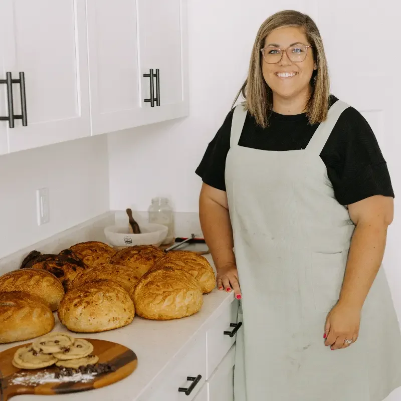 Elise in her kitchen beside a counter filled with freshly baked bread